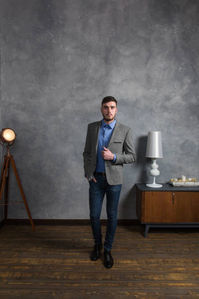 istock Handsome stylish young man standing in interior on gray background 1161000732