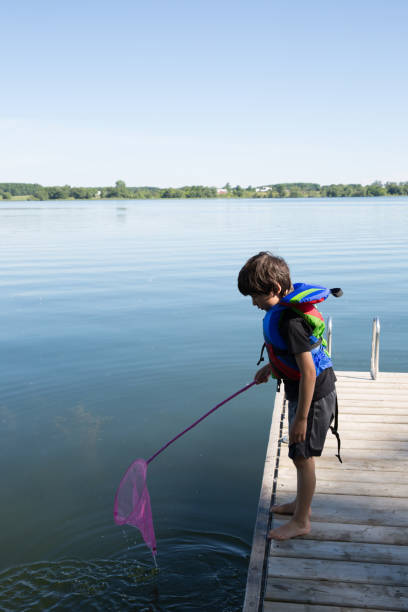 istock Little boy fishing on the dock with a net 1161001332