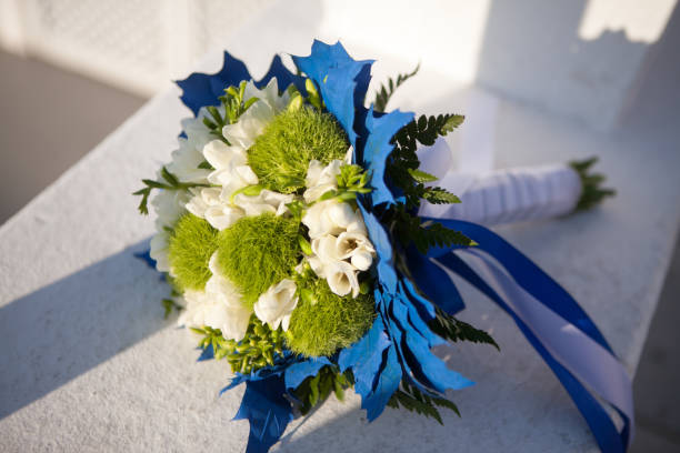 Wedding bouquet in white and green colors and blue decoration on a white surface