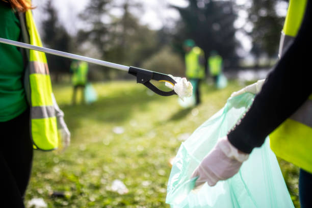 istock Two people cooperating in picking up trash in a local park 1161008254