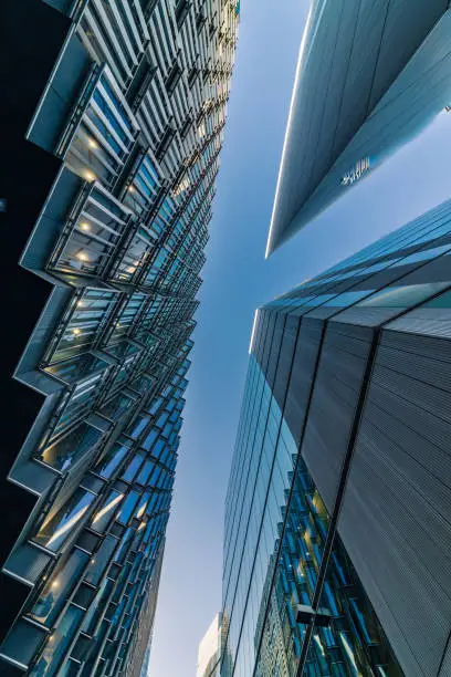Highly detailed abstract wide angle view up towards the sky in the financial district of London City and its ultra modern contemporary buildings. Shot on Canon EOS R system, 14mm wide angle prime lens. Colour edit with high contrast ideal for background with copy space.