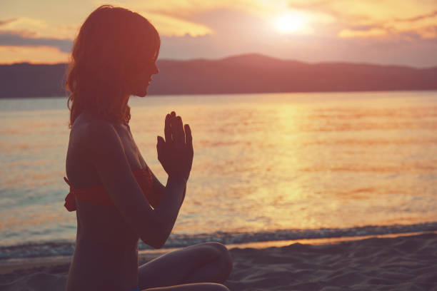 istock Young woman practicing yoga on the sandy beach. 1161010748