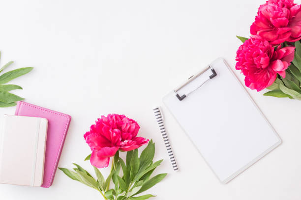 istock Flat lay blogger or freelancer workspace with a notebook, clipboard, red peonies on a white background 1161010972