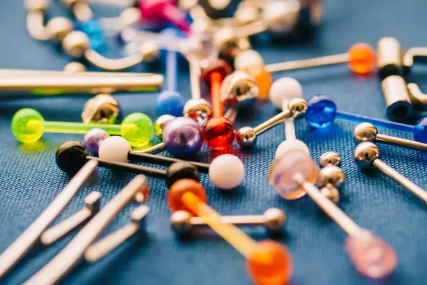 A closeup set of various piercing jewelry barbells and piercing instruments