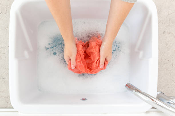istock Female hands washing color clothes in sink 1161011919