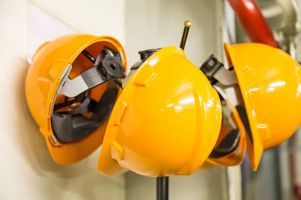 istock Yellow hard hat safety wear helmet hanging on coat rack at construction site 1161013220