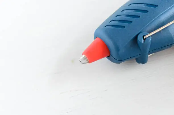 Blue glue gun and hot melt rods on white background.