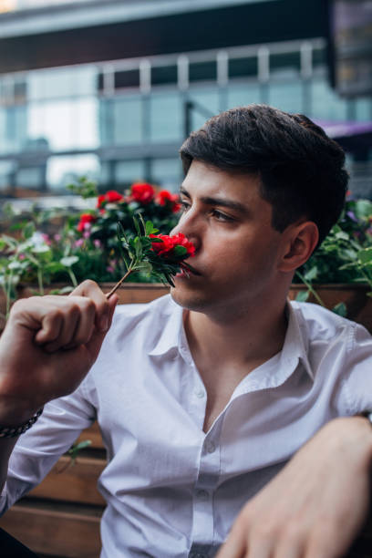 istock Handsome young man smelling red flower 1161025385