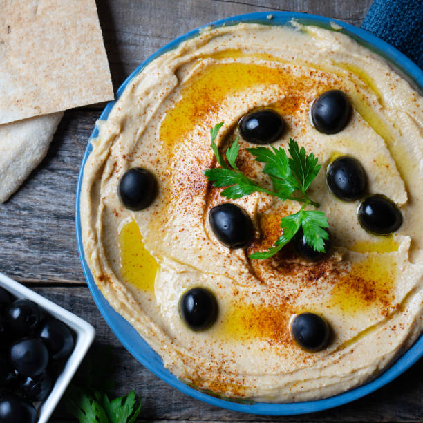 Traditional hummus plate with black olives and paprika