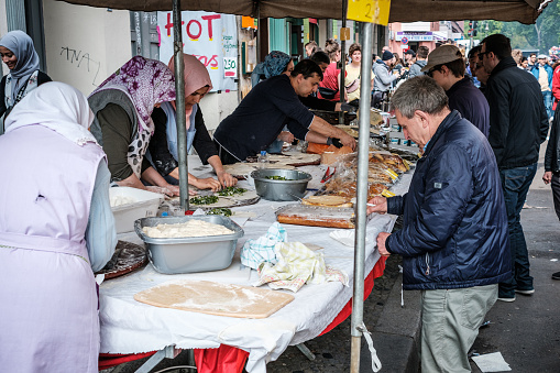 Berlin, Germany - May 01, 2019: Women preparing food on street market at myfest, labor day parade  on 1. mai, Berlin, Kreuzberg