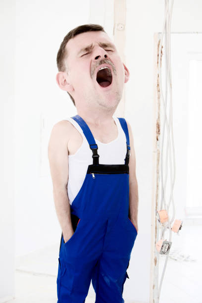 repairman with big head in a blue boilersuit is yawning repairman with big head in a blue boilersuit is yawning lazy construction laborer stock pictures, royalty-free photos & images