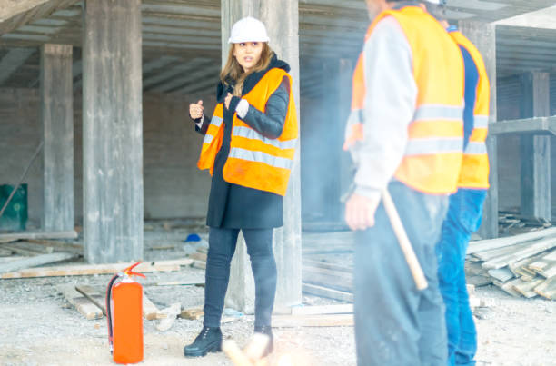 instruktorin erklärt, wie man feuerlöscher auf der baustelle verwendet - safety meeting construction site construction stock-fotos und bilder