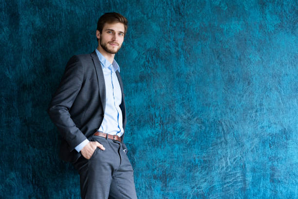 istock Portrait of handsome young man standing against blue wall with copy space. 1161042664