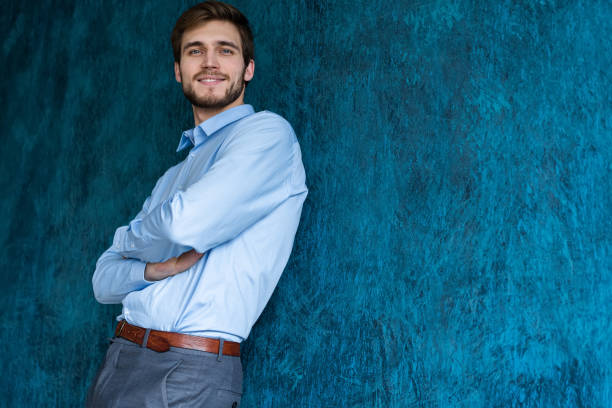 istock Portrait of handsome young man standing against blue wall with copy space. 1161042668