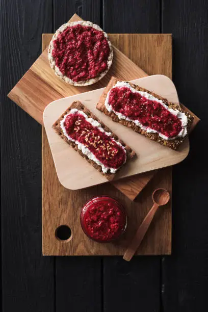 Superfood dessert. Chia seed raspberry jam with flax seeds and ricotta on wholegrain crispbread on black background top view copy space