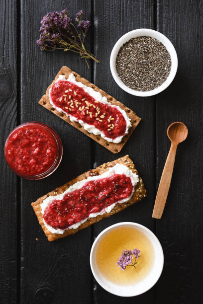 istock Healthy vegetarian snack. Chia seed raspberry jam with ricotta served with marjoram herbal tea on black background 1161043073