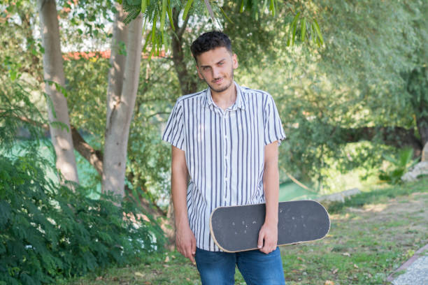 istock Skateboarder walking in natural parkland. 1161043939