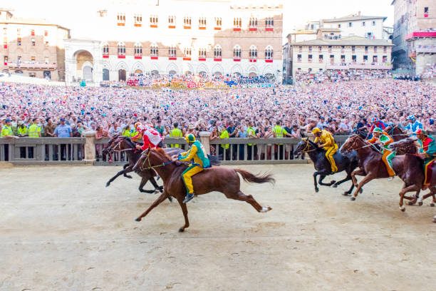2019年のパリオ・ディ・シエナの1周目に、イタリア・トスカーナのシエナ市にある「カンポ広場」で競い合う馬たち。 - torre del mangia ストックフォトと画像