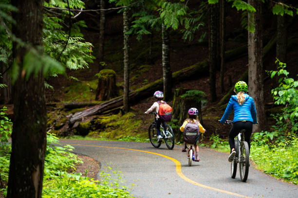 istock Mother and daughters cycling on road towards school 1161050124