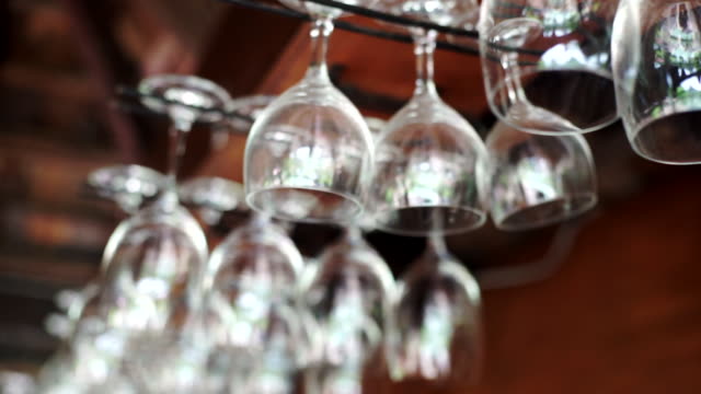 Group of empty wine glasses hanging above a bar rack.