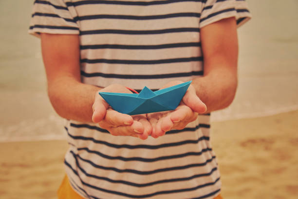 istock Man holding paper boat on tropical beach. 1161052636