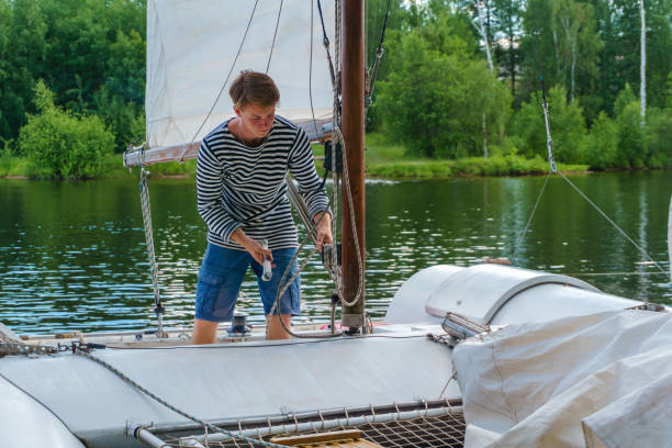 young sailor raises sail on a small sailing catamaran - buoy horizontal lake sailing imagens e fotografias de stock