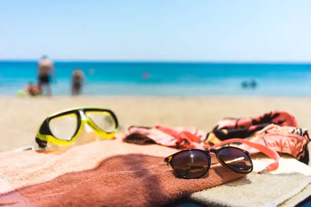 Photo of towel with different accessories on the beach