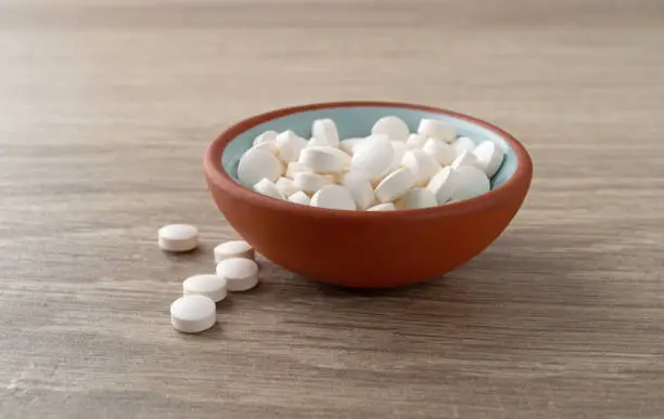 Photo of DHEA pills in a bowl on a table side view