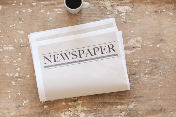 istock Newspaper and coffee on wooden background 1161060976