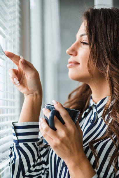 istock Young woman looking through the window and daydreaming 1161068259