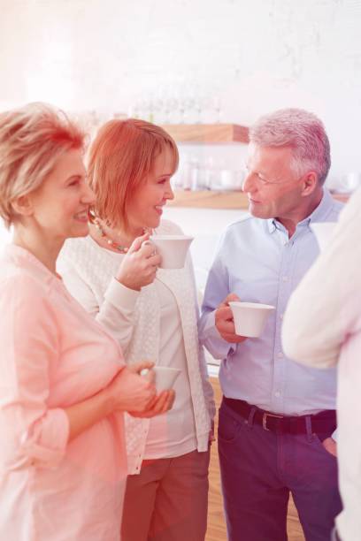 istock Mature friends talking while holding drinks at home 1161073660