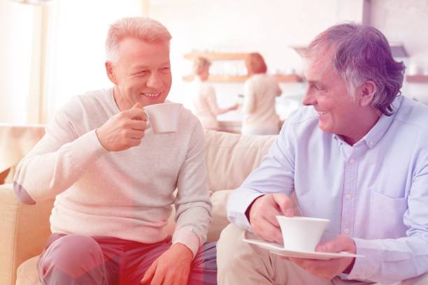 istock Smiling mature men holding coffee while sitting on sofa at home 1161073691