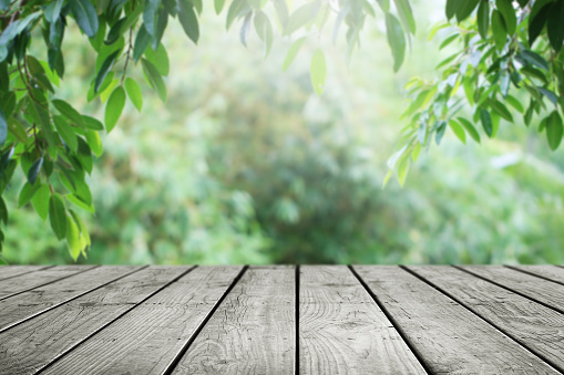 Wooden table and blurred leaf nature garden background.