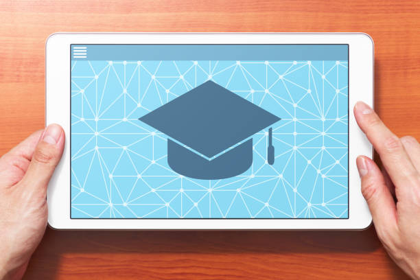 istock E-learning concept image. Closeup of hands touching white tablet computer on wooden desk. 1161075781