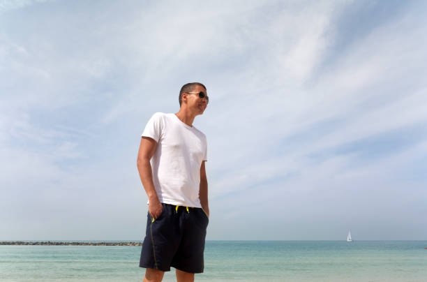 istock Tanned guy in white t-shirt on the beach 1161075985