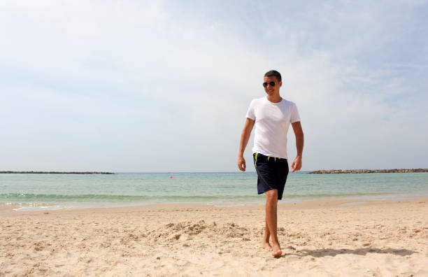 istock Tanned guy in white t-shirt on the beach 1161075995