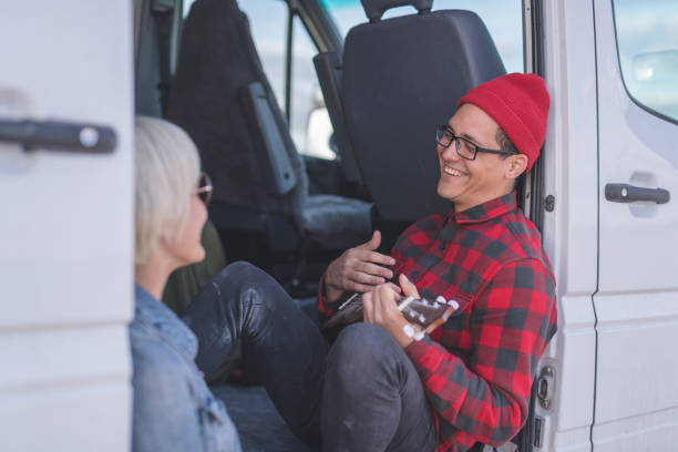 istock Hipster couple playing ukulele in their van on a camping trip 1161076078