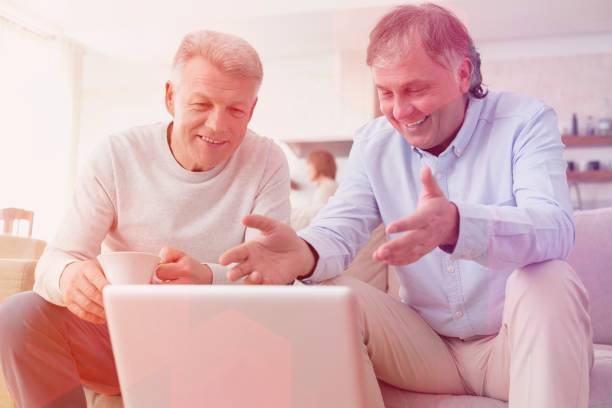 istock Smiling mature men using laptop while sitting at home 1161078345