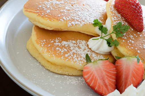 a plate of Japanese style thick fluffy pancakes accompanied with fresh strawberries