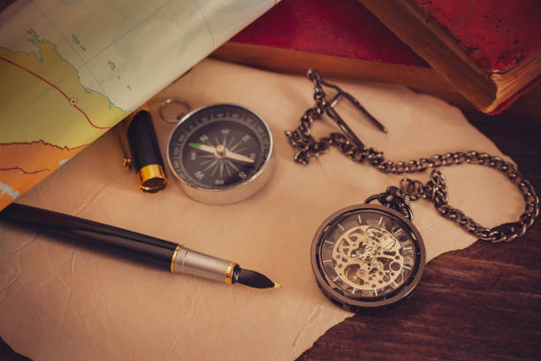 istock Pocket watch with old books and pen with paper map on the table. 1161081101