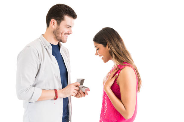 istock Smiling Man Showing Ring To Excited Girlfriend Against Plain Background 1161081175