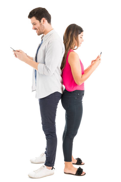 istock Fashionable Man And Woman Using Mobiles Against Plain Background 1161081444