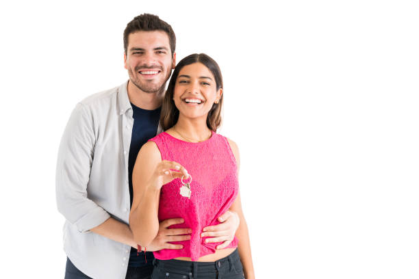 hispanic couple with keys against plain background - couple indoors studio shot horizontal imagens e fotografias de stock