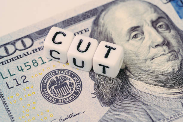 FED, Federal Reserve with interest rate cut concept, small cube block with alphabet building the word CUT next to Federal Reserve emblem on US Dollar banknote stock photo