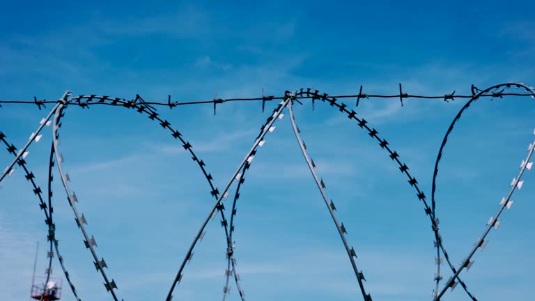 The fence with barbed wire on the background of a gloomy cloudy dark blue sky.