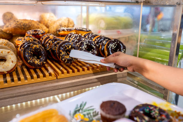 istock Human hand picking a delicious chocolate donut by clamp 1161087540