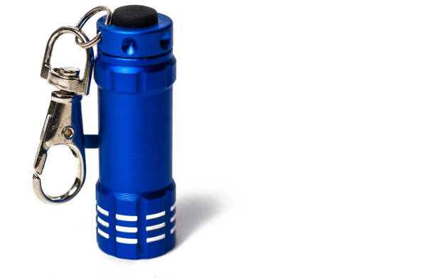 Standing Small metallic blue flashlight key chain on white paper background