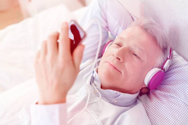istock Mature man looking at smartphone while lying on bed at home 1161109490