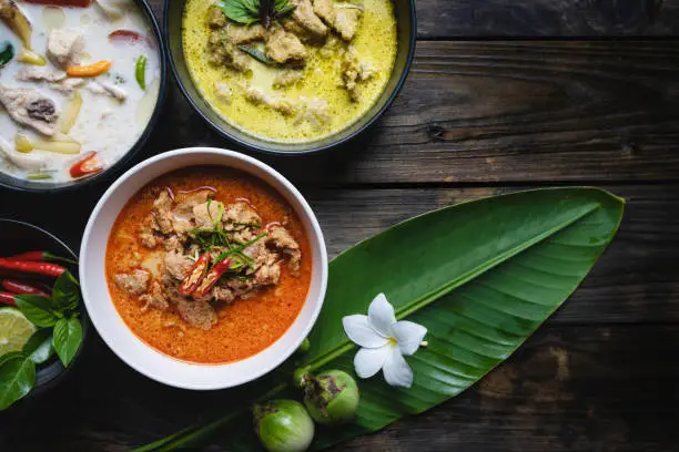 Most famous Thai foods; red curry pork, green curry pork, chicken coconut soup or Thai in names "Panang", "Kaeng Keaw Whan" and Tom Kha Gai. top view on wooden background.