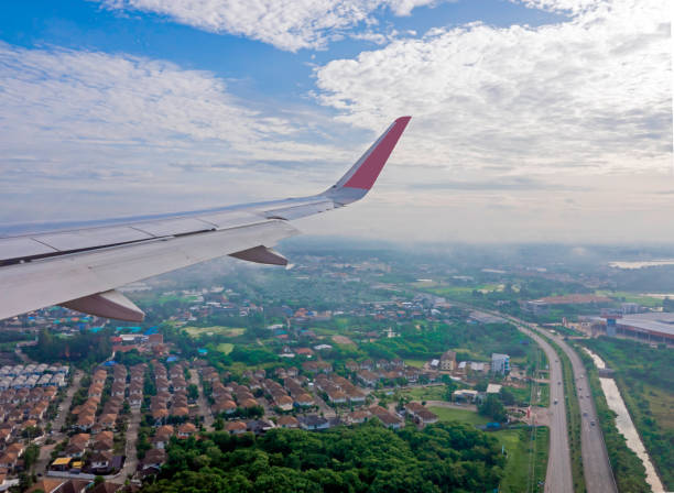 istock Airplane wings during the flight, viewed from the passenger window There are many white clouds in the blue sky above the ground, with views of Thailand below. 1161111513